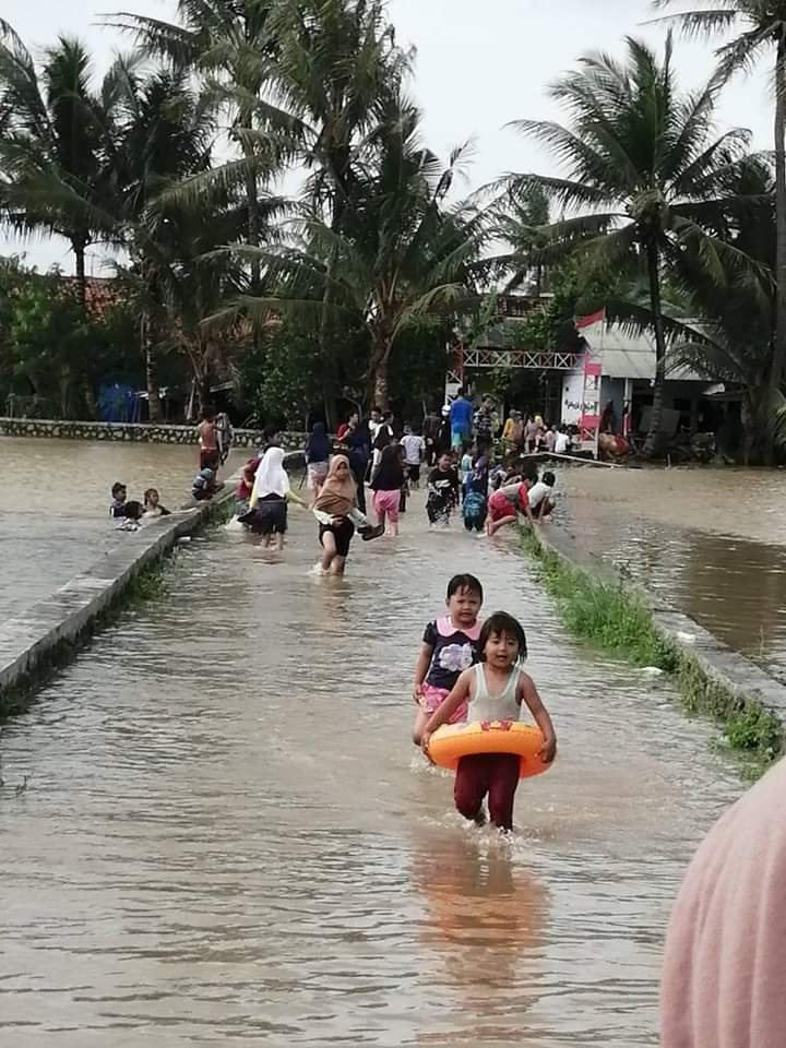 Sejumlah anak bermain di banjir yang menggenang di Kampung Sirnagalih, Desa Kaliasin, Kecamatan Sukamulya, Kabupaten Tangerang setelah hujan yang mengguyur, Sabtu malam, (21/2/2021).